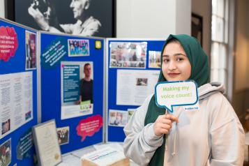 Young girl standing in front of a Healthwatch notice board